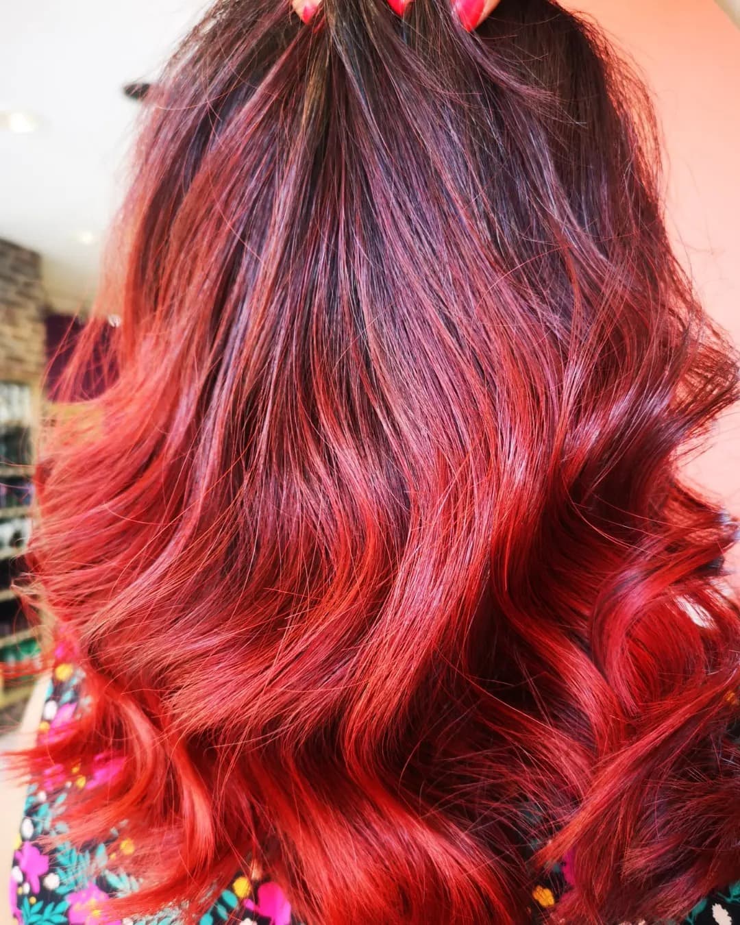 Coloration rouge intense en dégradé sur cheveux longs ondulés