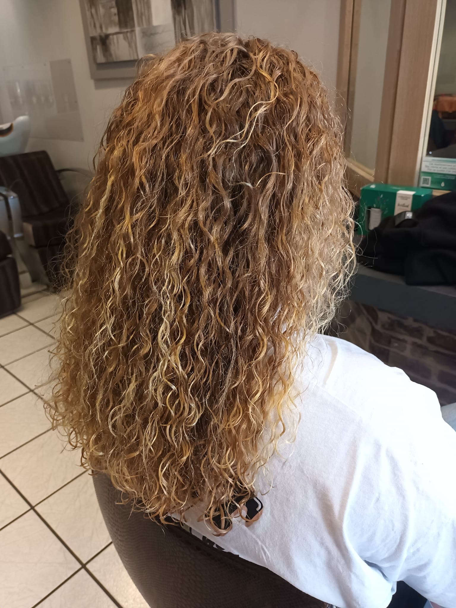Boucles serrées et coloration blond doré sur cheveux longs